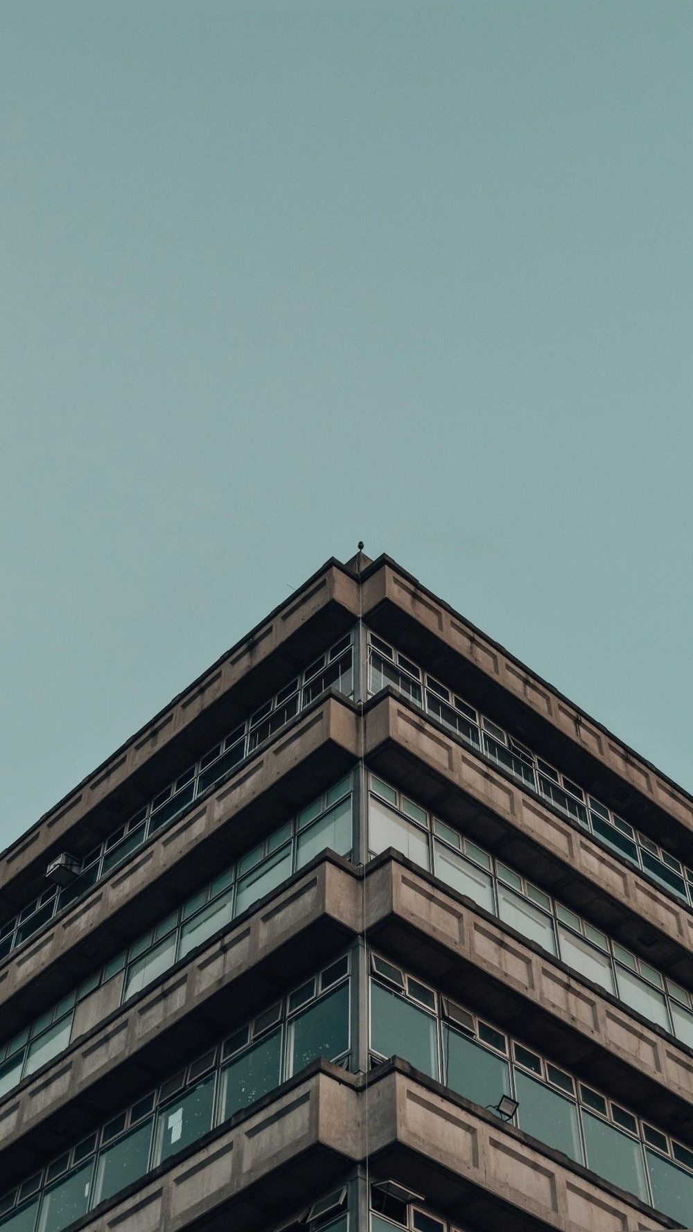 The stepped concrete corner of a building against a flat sky