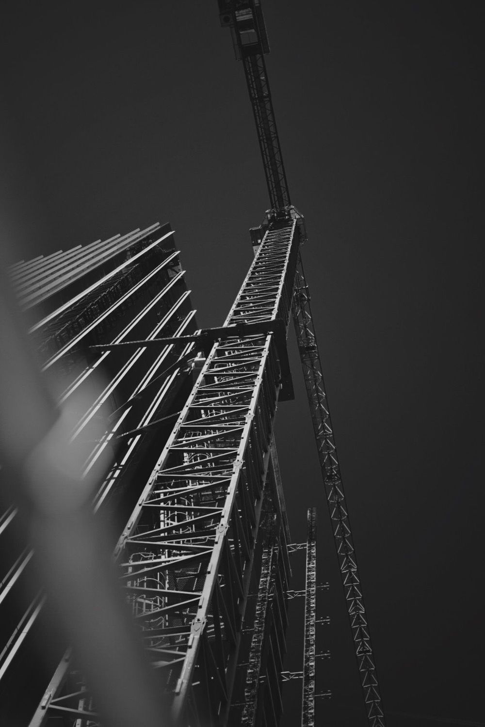 A tower crane mast rising beside a building under construction, seen from below