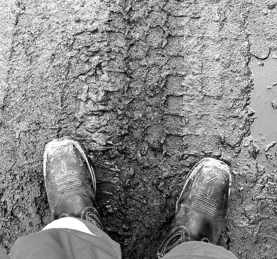 Overhead view of work boots standing in mud and concrete formwork on a job site